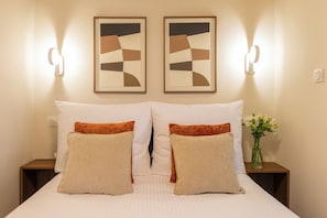 A hotel room with a bed, two wall-mounted light fixtures, and a vase with flowers. - Native Apartments Węgierska 10  (Kraków)