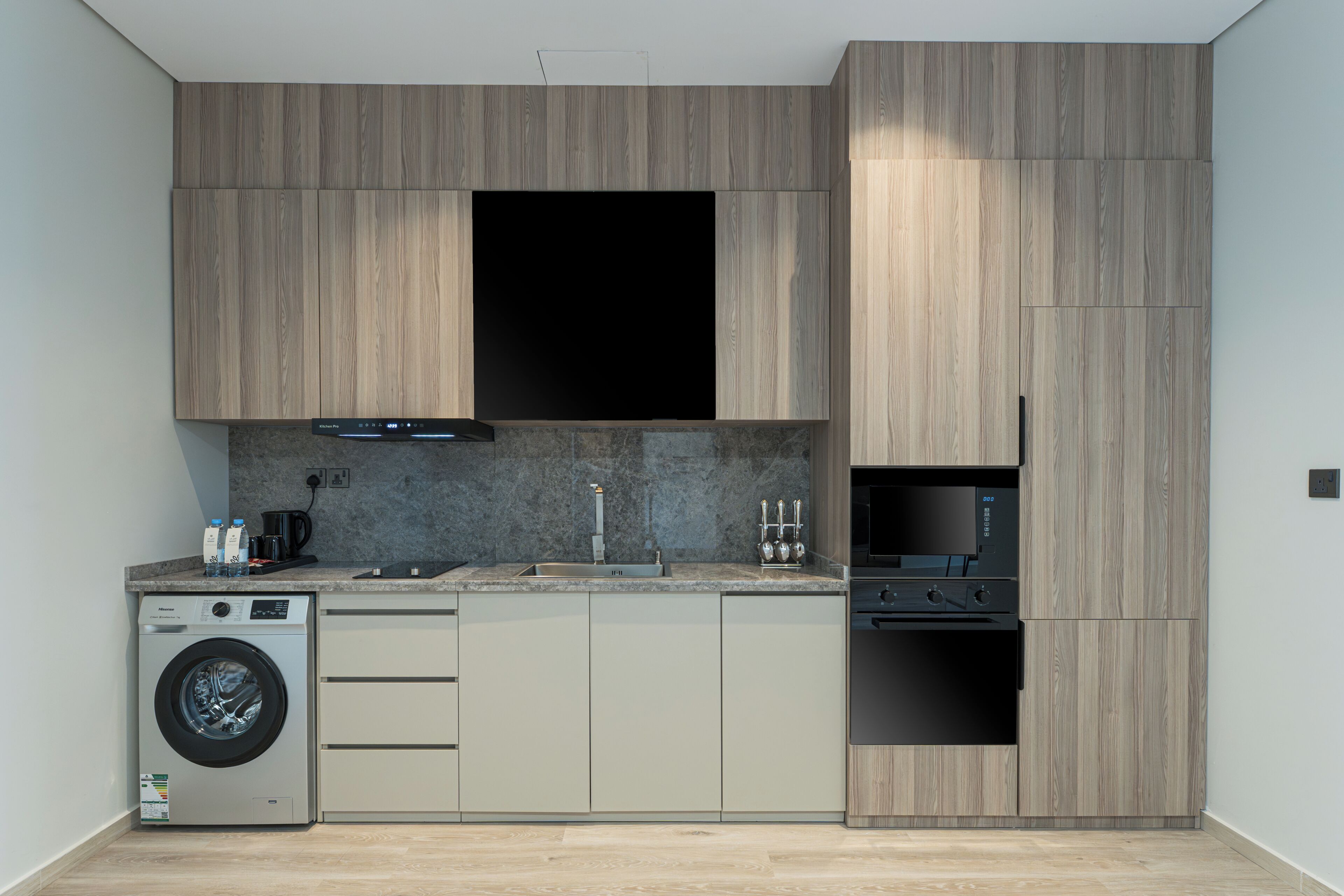 Una cocina moderna con electrodomésticos integrados, lavadora y un amplio ventanal.