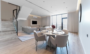 Uma sala de estar moderna com área de jantar, escada e uma janela grande.