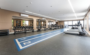 A gym with treadmills, weight machines, and dumbbells. - Lafeef Apartments Al-Namuzji (Madinah)