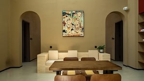 Un interior moderno con zona de comedor, asientos acolchados y una obra de arte colgada en la pared.