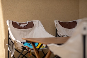Two white folding chairs with brown seat cushions against a beige wall.