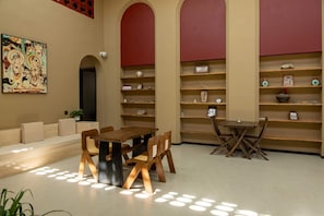 A modern interior with a dining table, chairs, a sofa, and a bookshelf.