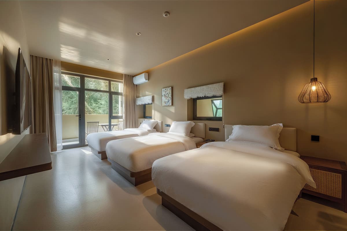 A hotel room with two beds, a TV, a balcony, and a large window.