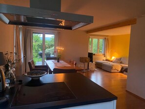 A modern kitchen with a dining area, a sofa, and a view of the outdoors. - Charming Family House in Herrliberg With Garden Views (Herrliberg)