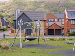 A residential area with houses, a swing set, and a paved driveway. - Beacon View (Malvern)