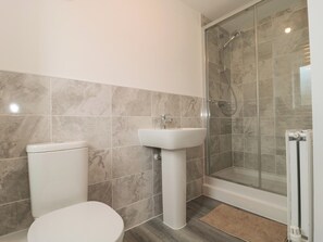 A bathroom with a toilet, sink, shower, and a glass-enclosed shower stall. - Beacon View (Malvern)
