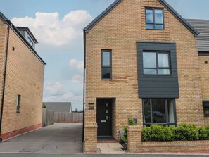 A two-story residential building with a brick facade, a black-framed window, and a visible door. - Beacon View (Malvern)