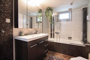 Uma casa de banho moderna com um espelho grande, uma pia, um chuveiro e uma parede com padrão escuro.
