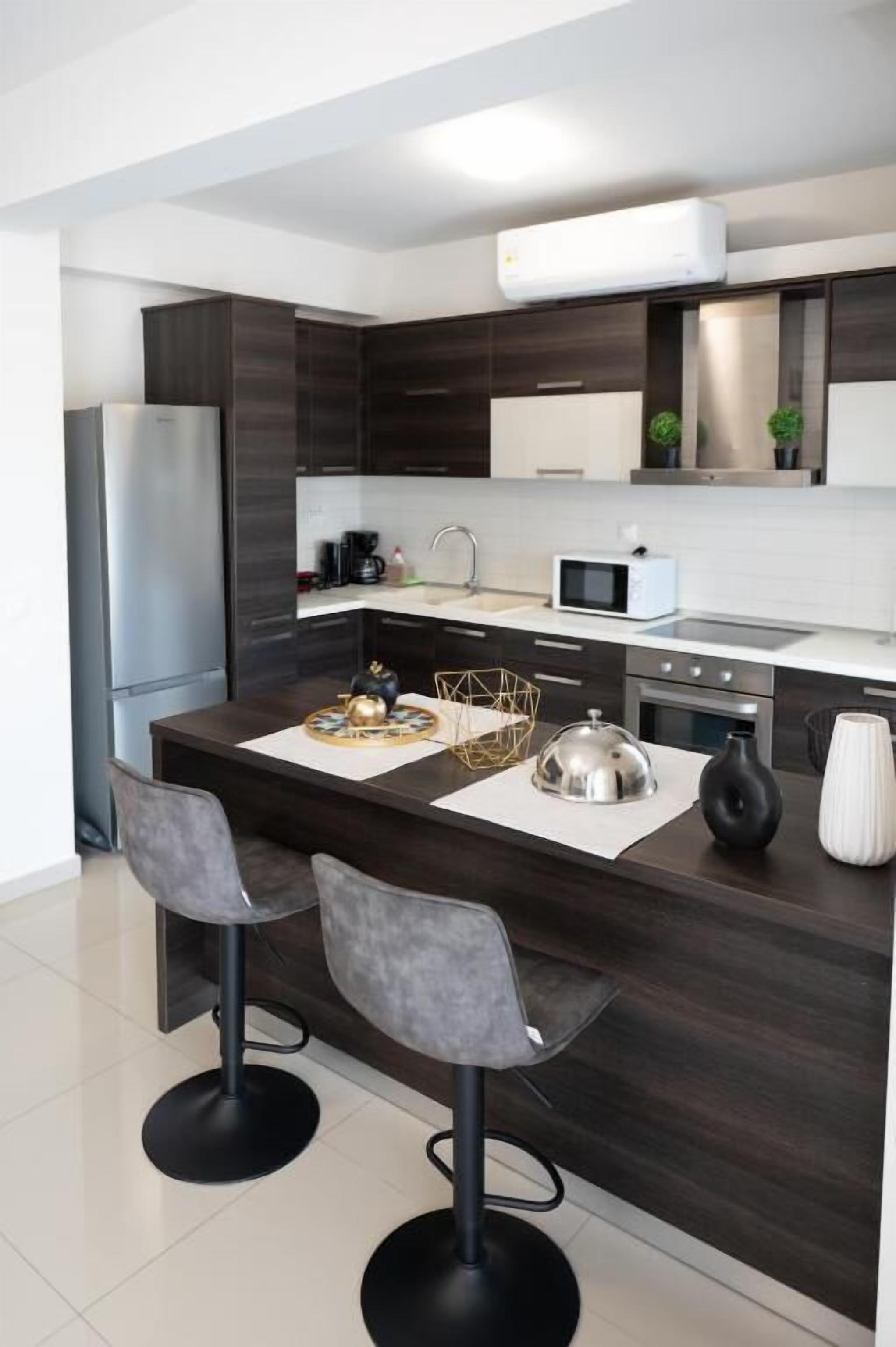 A modern kitchen with dark wood cabinets, stainless steel appliances, and a central island with bar stools.