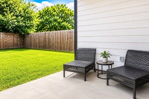 Eine Terrasse mit zwei Korbstühlen, einem kleinen runden Tisch und einem Blumentopf.