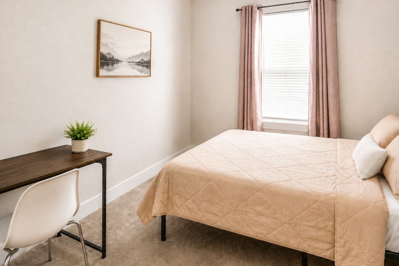 Ein Schlafzimmer mit Bett, Schreibtisch, Stuhl, einem Fenster mit Vorhängen und einem gerahmten Bild an der Wand.