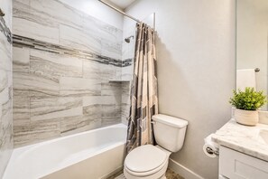 Ein Badezimmer mit Badewanne, Toilette, Duschvorhang und einer Topfpflanze.