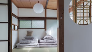 A traditional Japanese room with tatami flooring, a futon bed, shoji screens, and a hanging paper lantern.