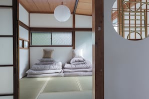 A traditional Japanese room with tatami flooring, a futon bed, shoji screens, and a hanging paper lantern.