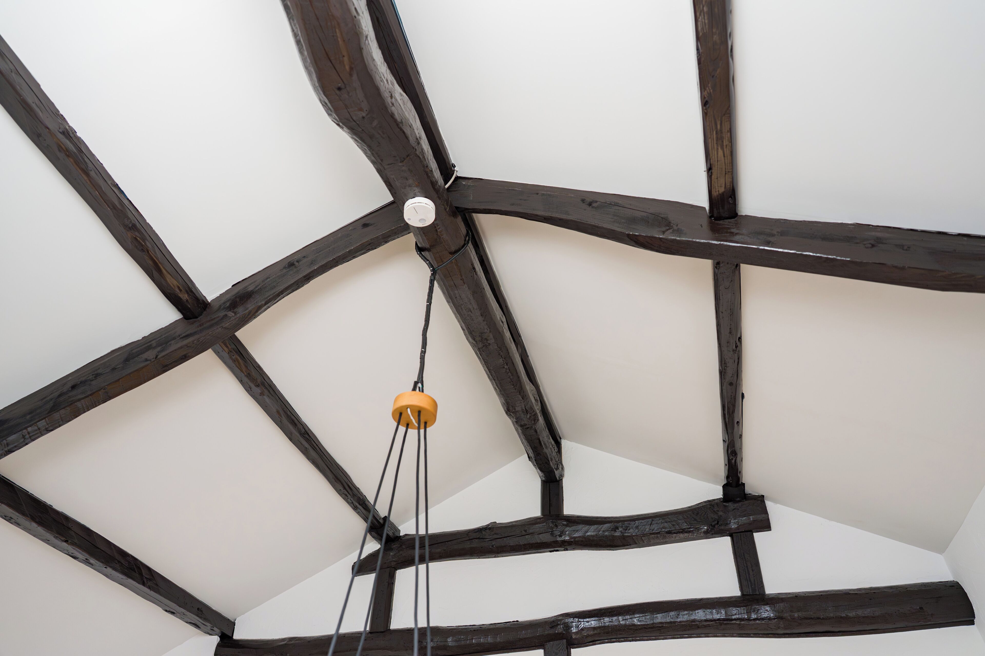 A ceiling with exposed wooden beams and a hanging light fixture.