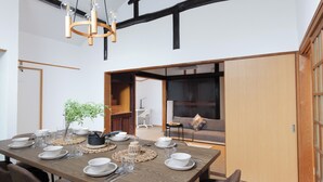 A dining area with a wooden table set for four, surrounded by chairs, with a hanging light fixture above.