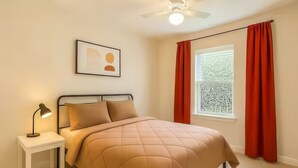 A bedroom with a bed, a nightstand, a lamp, a ceiling fan, and a window with curtains. - Reed Unit B - Quiet Solo Room w/Shared Bath in Co-Living Home (Houston)