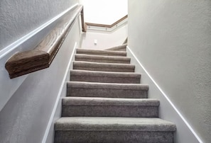 A staircase with carpeted steps and wooden handrails. - Reed Unit B - Entire Spacious 4BR Home (Houston)