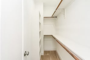 A narrow hallway with white walls, wooden flooring, and a door on the left. - Reed Unit B - Entire Spacious 4BR Home (Houston)