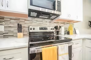 A kitchen with a stainless steel oven, a microwave, and a tiled backsplash. - Reed Unit B - Entire Spacious 4BR Home (Houston)