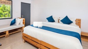 A bedroom with a wooden bed, a bench, and a window with a view of greenery. - Farm Aravalia (Faridabad)