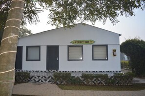 A building with a reception sign, a door, and windows. - Farm Aravalia (Faridabad)