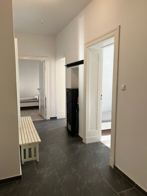 A hallway with a bench, a wardrobe, and a bed in the background. - Steglitz V-large apartment in old building, 3 rooms, kitchen, bathroom & balcony (Berlin)