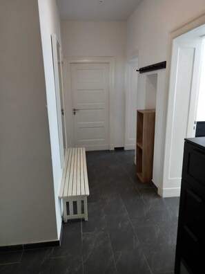 Ein Flur mit einer weißen Tür, einer hölzernen Bank und einem schwarzen Schrank.
