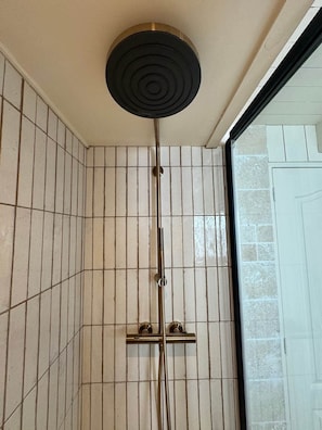 Une douche dotĂ©e dâun pommeau circulaire, dâune barre verticale et dâune barre horizontale.
