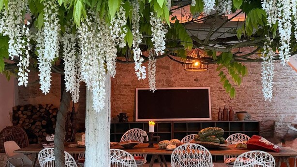 A rustic outdoor dining area with white wicker chairs, a wooden table, and hanging white flowers. - Criste Marine Deluxe Suite (LE BOIS PLAGE EN RE)
