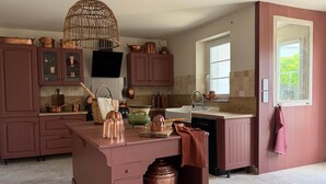 A kitchen with a central island, copper cookware, and a hanging light fixture. - Criste Marine Deluxe Suite (LE BOIS PLAGE EN RE)