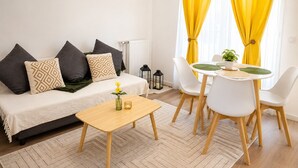 Ein modernes Wohnzimmer mit einer Couch, einem kleinen Tisch und einem Essbereich mit Stühlen.