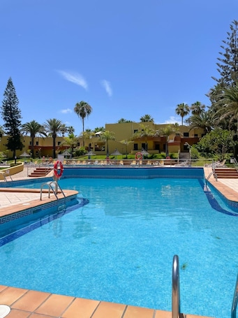 A swimming pool with a lifebuoy, lounge chairs, and palm trees.. Vacation Apartment 'B-rent Atlantic Garden 181' with Shared Pool, Wi-Fi and Air Conditioning