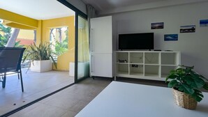 Ein modernes Wohnzimmer mit Flachbildfernseher, einem weißen Schrank und einem Topfpflanzen.