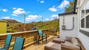 Um terraço com mobiliário ao ar livre, vista para a paisagem e uma casa com revestimento.