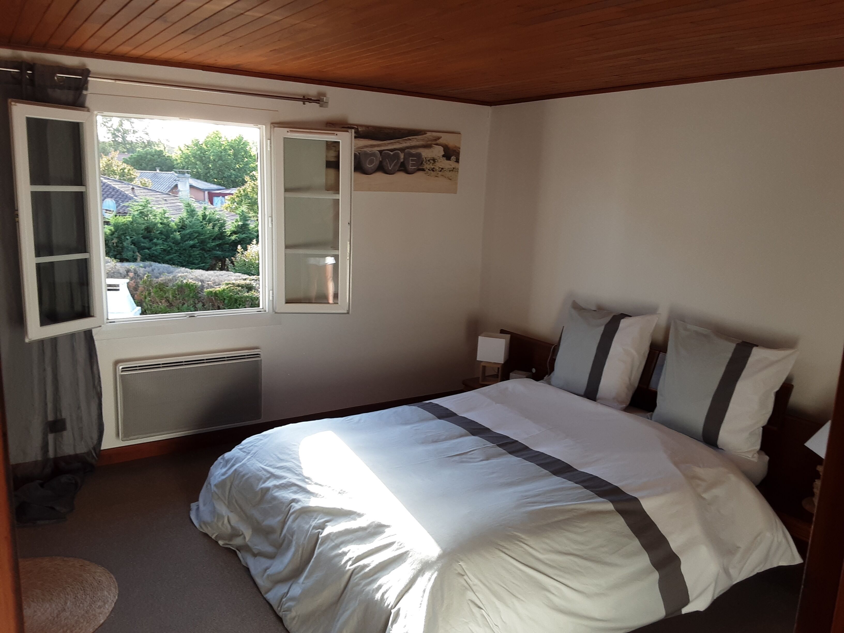 Een slaapkamer met een bed, een raam, een radiator en een klein nachtkastje.
