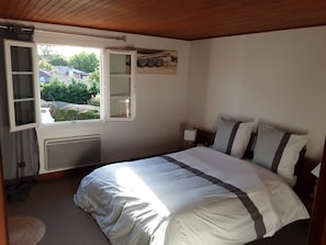 A bedroom with a bed, a window, a radiator, and a small bedside table. - Maison de caractère .La vague douce des Landes (Vielle-Saint-Girons)