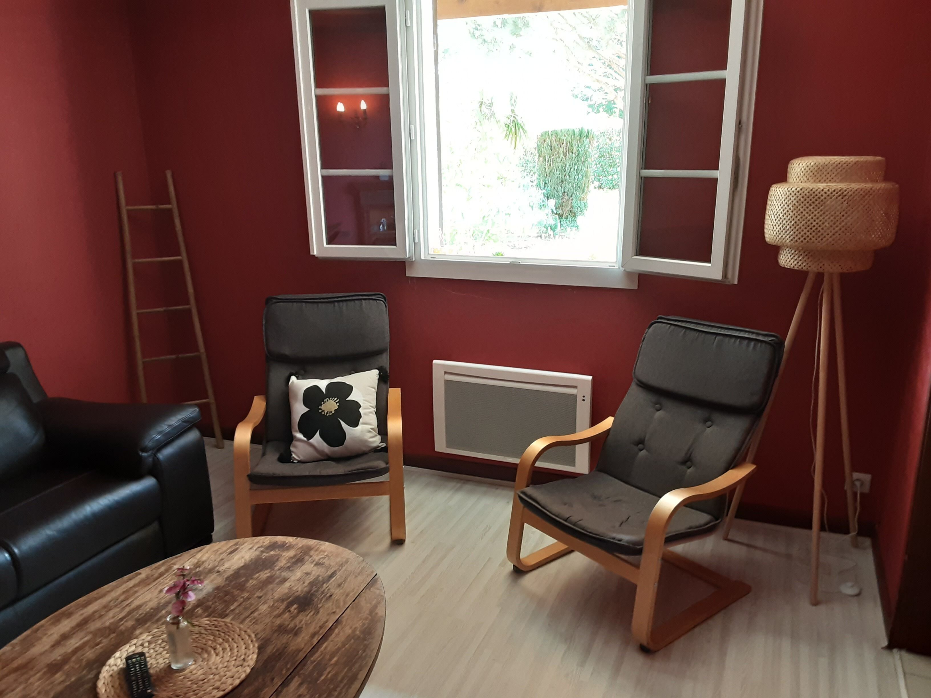 Een kamer met twee zwarte leren banken, een houten salontafel met een vaas en afstandsbediening, en een vloerlamp.