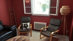 Una habitación con dos sofás de cuero negro, una mesa de centro de madera con un jarrón y un control remoto, y una lámpara de pie.