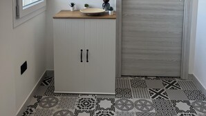 Un couloir avec une armoire blanche, un comptoir en bois, une porte et des carreaux de sol à motifs.