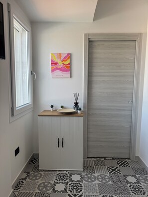 Ein Flur mit einem weißen Schrank, einer Holztischplatte, einer Tür und Fliesen mit Muster.