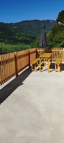 A wooden deck with a table and benches, overlooking a green valley and mountains.. Holiday Home 'Ferienhaus Sonnseitn' with Mountain View, Private Terrace and Private Garden