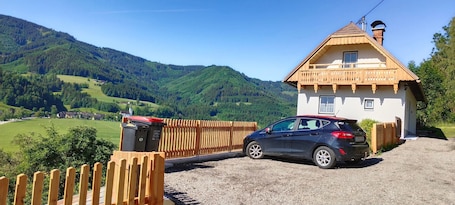 A house with a balcony, a car parked in front, and a wooden fence.. Holiday Home 'Ferienhaus Sonnseitn' with Mountain View, Private Terrace and Private Garden