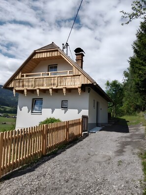A chalet-style house with a balcony, a chimney, and a gravel driveway. - Holiday Home 'Ferienhaus Sonnseitn' with Mountain View, Private Terrace and Private Garden (Altlassing)