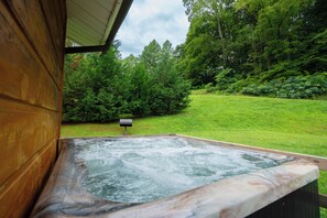 A hot tub with a wooden deck and a view of a grassy area with trees. - 🍃 Quaint Cabin on Cosby Creek 🏞️ Creekside Farm, Hot Tub & Park Access (Cosby)