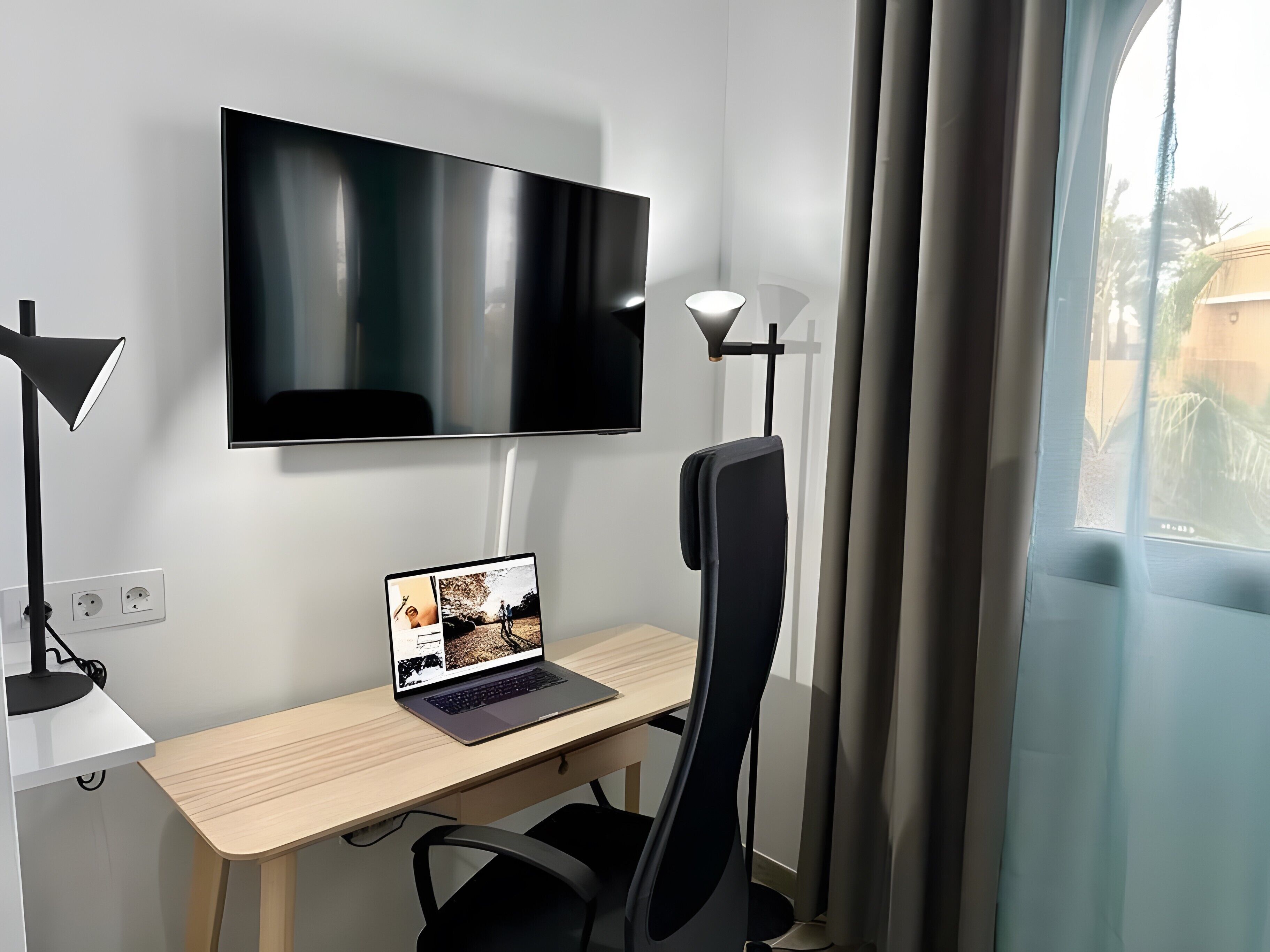 Une chambre moderne équipée d’un bureau, d’un ordinateur portable, d’une télévision et d’une chaise.