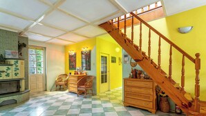 A room with a checkered floor, a wooden staircase, and a door leading to another room. - Scenic Riverside House with Beautiful Views (Litwinki)