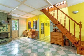 A room with a checkered floor, a wooden staircase, and a door leading to another room.