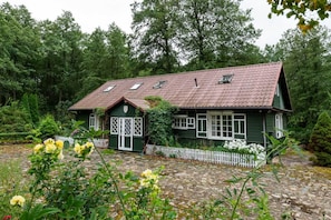 Une maison verte avec un toit en tuiles, des fenêtres blanches et une clôture en bois peinte en blanc.